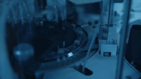Tracking shot of automated laboratory analyzer dispensing liquid into vials on rotating carousel in sterile laboratory. - Powered by Shutterstock - Get 15% off with code: PIKWIZARD15