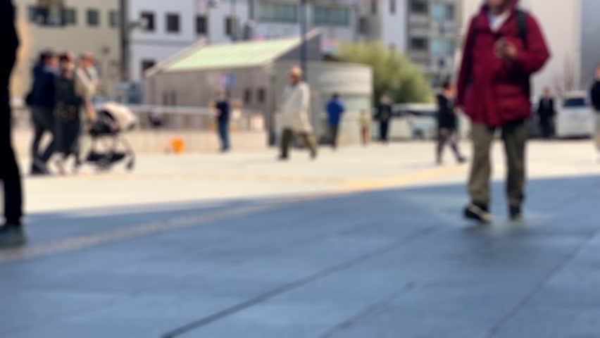 Blurred people walking in modern urban plaza with buildings background