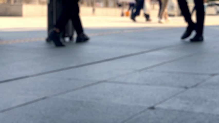 Blurred people walking in modern urban plaza with buildings background