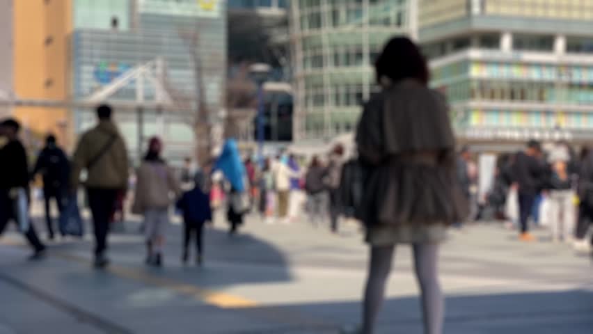 Blurred people walking in modern urban plaza with buildings background