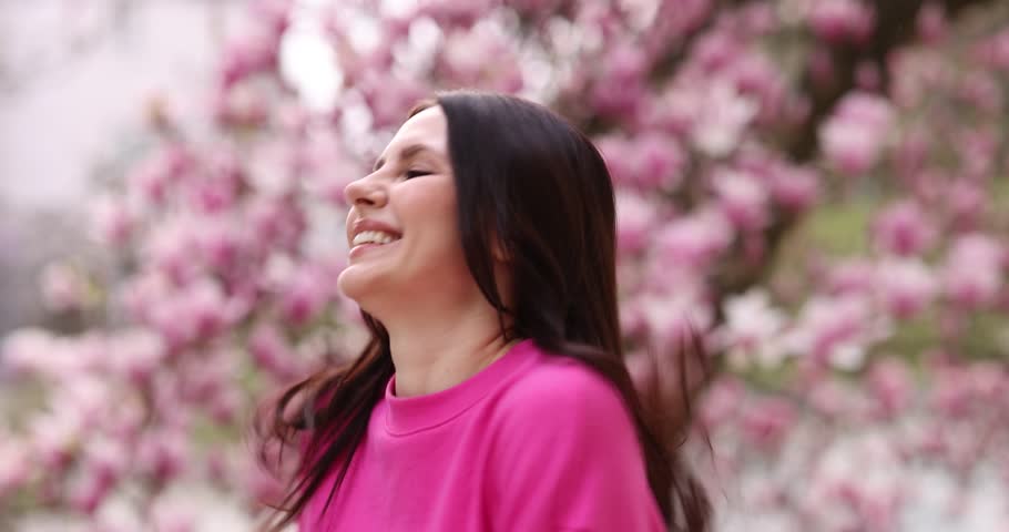 Beautiful woman in park with blossoming magnolia trees