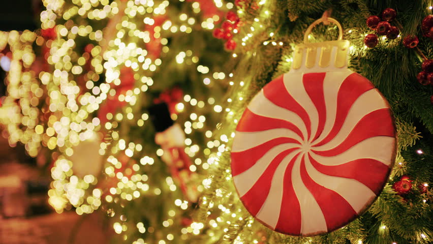 Christmas tree decorated with warm lights and a large red and white peppermint style ornament
