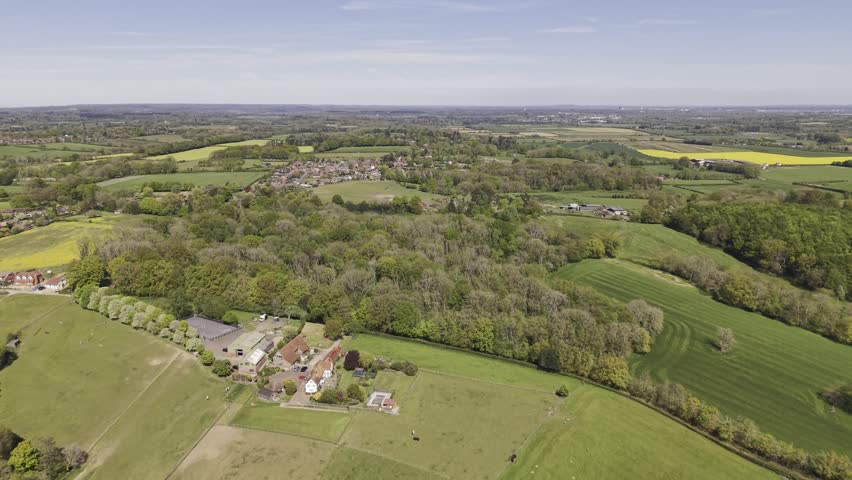4K aerial drone footage over spring rural landscape of farm fields and woodland in English countryside, West Berkshire, UK