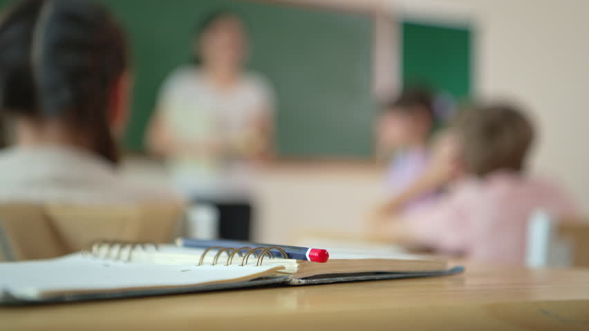 Notebook and pencil on desk with blurred classroom background, ideal for copy space and education concept