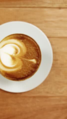 Close-up of coffee cup with saucer on wooden table 4k