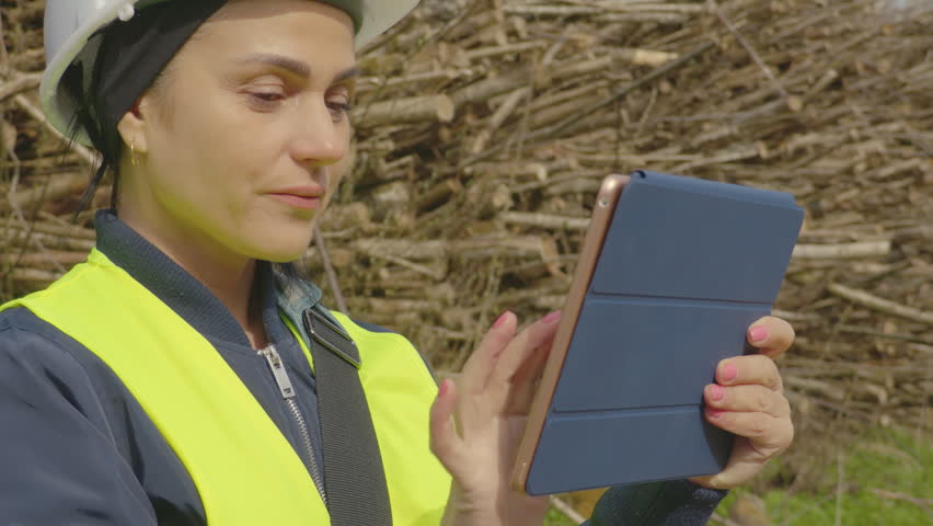 Woman with a tablet PC near cutted branches
