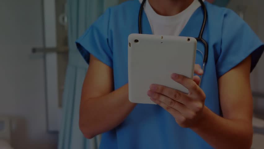 Male clinician tapping tablet and activating digit stream while reviewing records, stethoscope. Clinic, hospital, medical, scrubs, doctor, pediatric, smiling
