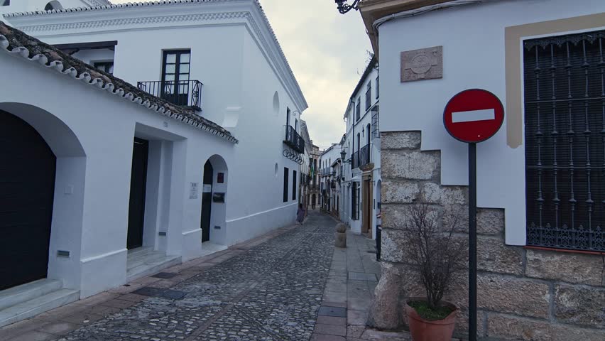 Cinematic shot of a traditional white-washed street in Ronda, Malaga. Iconic Andalusian architecture, cobblestones, and rustic charm.