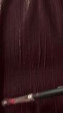 A short vertical close-up video showing a wide flat brush applying and spreading deep dark burgundy and maroon acrylic paint in long vertical strokes across the entire canvas surface. The glossy, wet paint fills the whole frame with rich, dark wine tones, with visible fine brushstroke lines catching the light and creating subtle texture variations. The brush is partially visible at the top right corner, actively painting downward. The moody, dramatic color and rhythmic brush motion create a powerful and atmospheric visual suitable for art, creative process, and dark abstract design concepts. - Powered by Shutterstock - Get 15% off with code: PIKWIZARD15