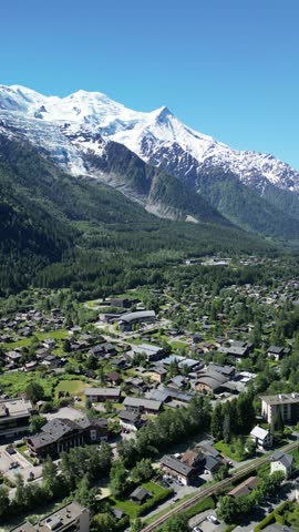 Aerial view of Chamonix town nestled in the French Alps. Cinematic drone shot of the famous mountain resort valley with majestic snowy peaks in the background.