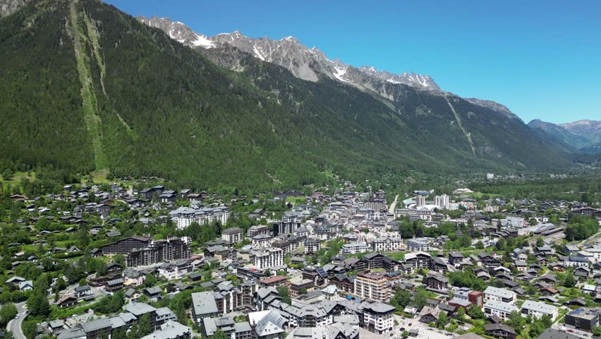 Aerial view of Chamonix town nestled in the French Alps. Cinematic drone shot of the famous mountain resort valley with majestic snowy peaks in the background.