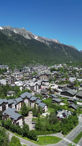Aerial view of Chamonix town nestled in the French Alps. Cinematic drone shot of the famous mountain resort valley with majestic snowy peaks in the background.