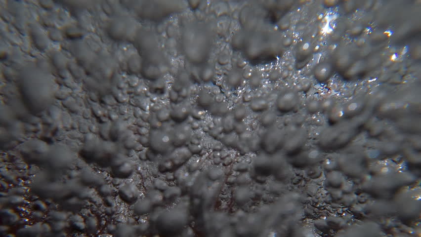 Rapid, chaotic movement of air bubbles in fast underwater current, natural background. Close-up of oxygen in rapid stream quickly rushing above camera