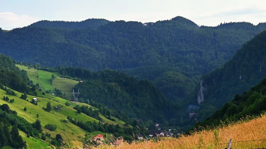 Aerial-style landscape of green hills and forest valley, peaceful mountain countryside scenery.