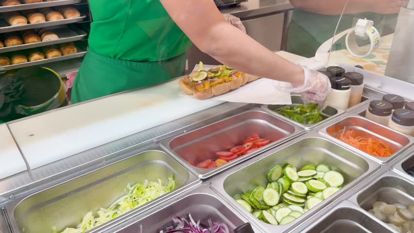  Preparing delicious sandwich with fresh vegetables and meat in fast food restaurant.