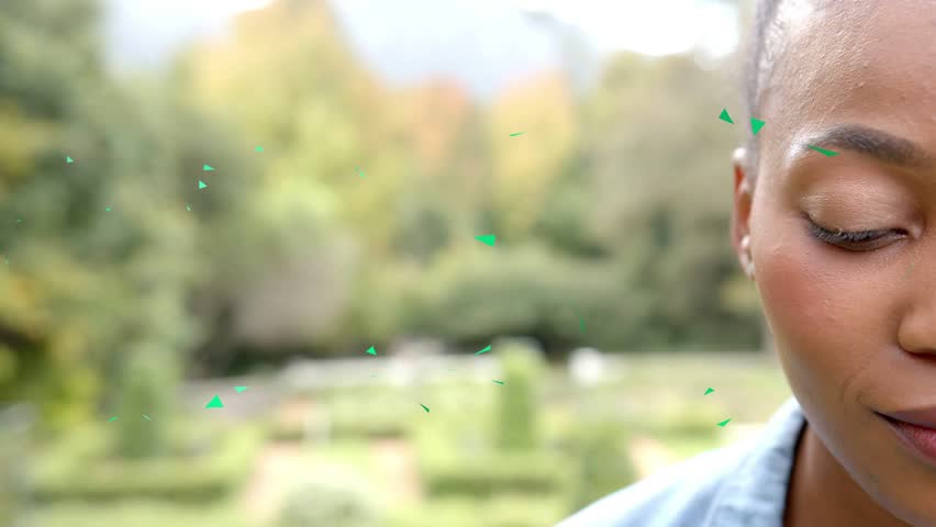 Woman in right closeup, green triangles drifting across face, gaze shifting, smiling, marketing. Portrait, outdoor, garden, autumn, bokeh, softfocus, confetti