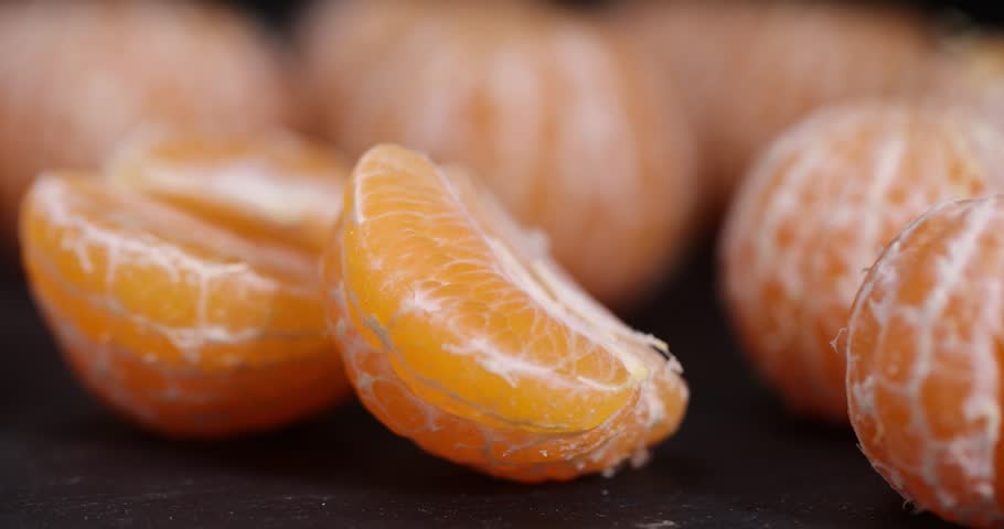 sliced peeled orange tangerine on a black slate table, ripe orange small mandarin without peel on a black slate board, tangerine divided into small slices