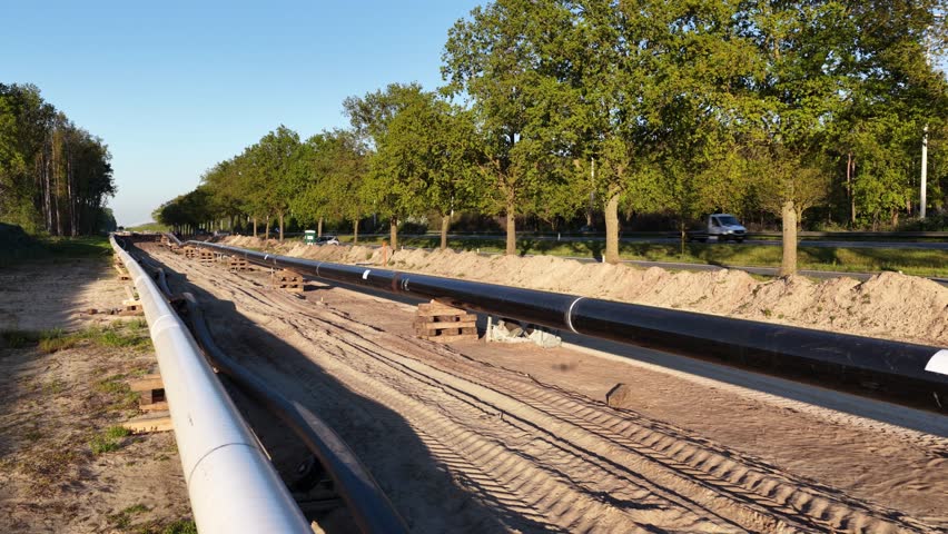New pipeline installation underway in sunny treelined landscape