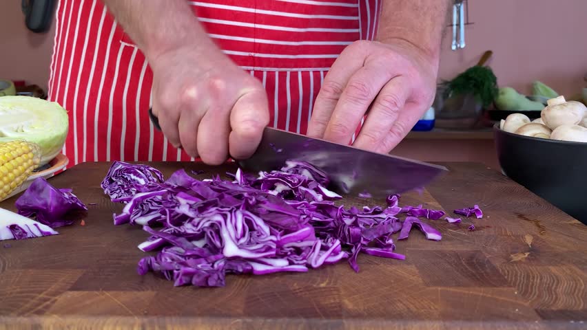 Chef preparing healthy vegetables, chopping fresh purple cabbage on a wooden board, cooking nutritious meal ingredients.