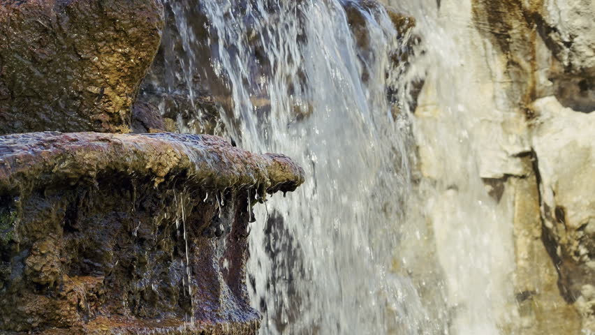 Scenic high-angle view looking down on a cascading waterfall from wet rocky cliffs. Pure water flows through a wild natural landscape. Perfect for nature, travel, and adventure content in high resolution.
