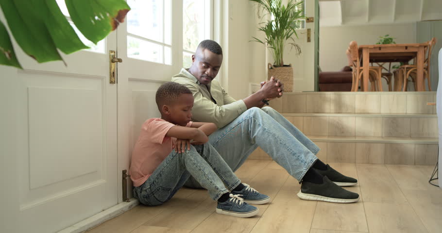 African American father and son starting talk, calming quiet child, sitting on floor by glass door. Family, parenting, conversation, bonding, guidance, comfort, entryway
