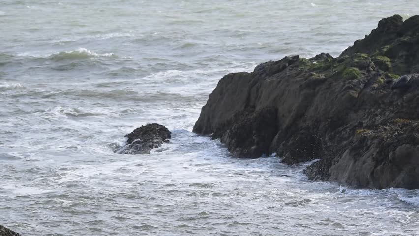 strong stormy waves hitting dramatic rocky shore with big splashes