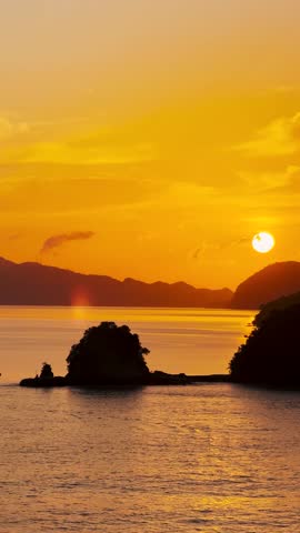 Vertical shot of sun rising above ocean at Langkawi Island, Malaysia. Orange clouds in sky during sunrise. Sun rising above the Strait of Malacca with little islands of Langkawi. Nature background.