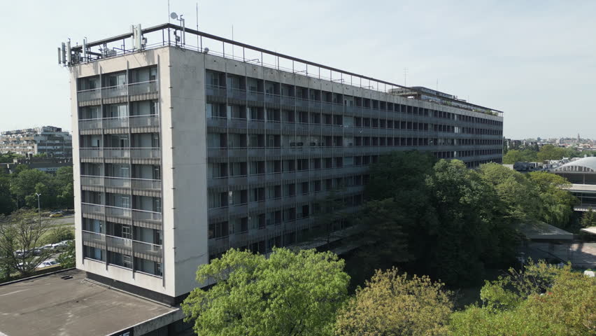 Cinematic flight towards an abandoned Socialist Modernist hotel, capturing derelict concrete architecture, New Belgrade, Serbia.