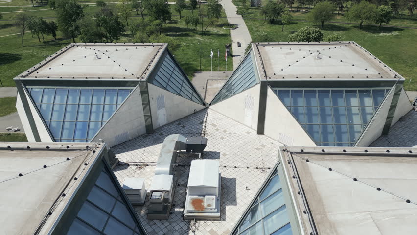 Low-altitude drone flight over the sharp triangular roof of a Socialist Brutalist building in New Belgrade, Serbia.