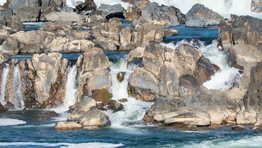 View of Great Falls Park with powerful waterfalls cascading over jagged rock formations and white water rapids in McLean, Virginia, United States.