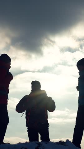 Tourists meet at mountaintop, success. Travelers climbers climb to top snowy mountain celebrate victory backdrop winter sunset. Teamwork in business, victory success. Victory success business people