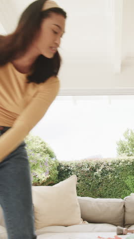 Vertical video: Spotting confetti, Asian woman sweeping, collecting debris on patio for cleaning. Cleaning, household, maintenance, domestic, organizational, minimalism, vertical video