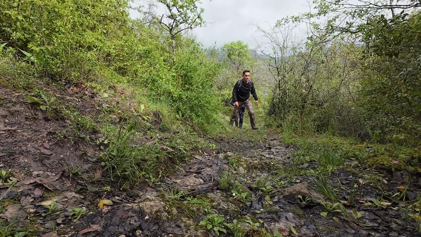Two hikers descending muddy trail in green forest