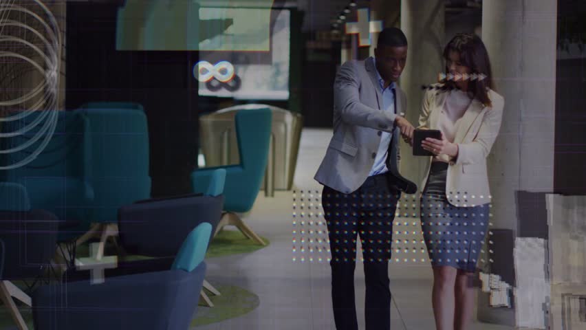 Team walking hall, man pointing tablet while woman tapping, reviewing as business visuals appear. Collaboration, corridor, lounge, colleagues, discussion, gestures, touchscreen