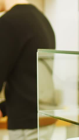 Mid section of man keeping tray of croissants in display case of coffee shop