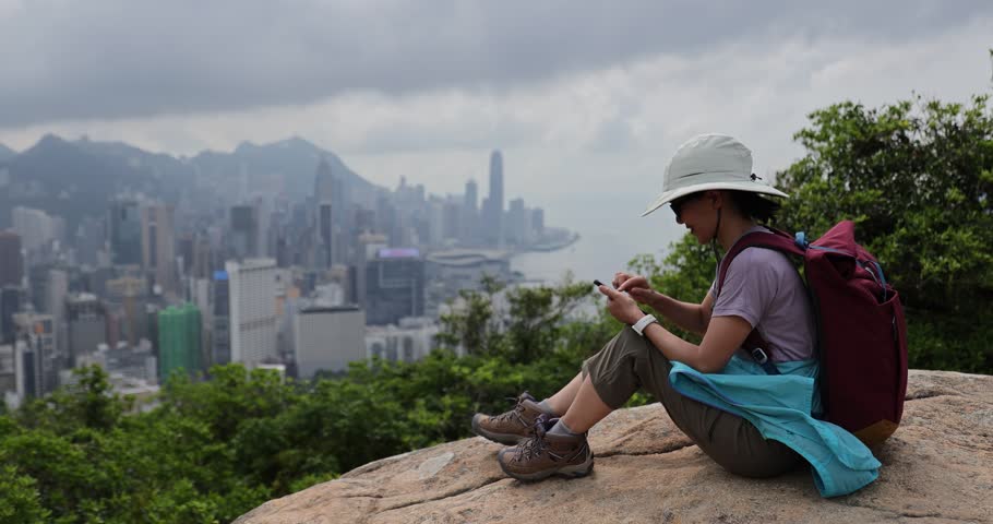 Woman hike using phone at the mountain top in Hong Kong	