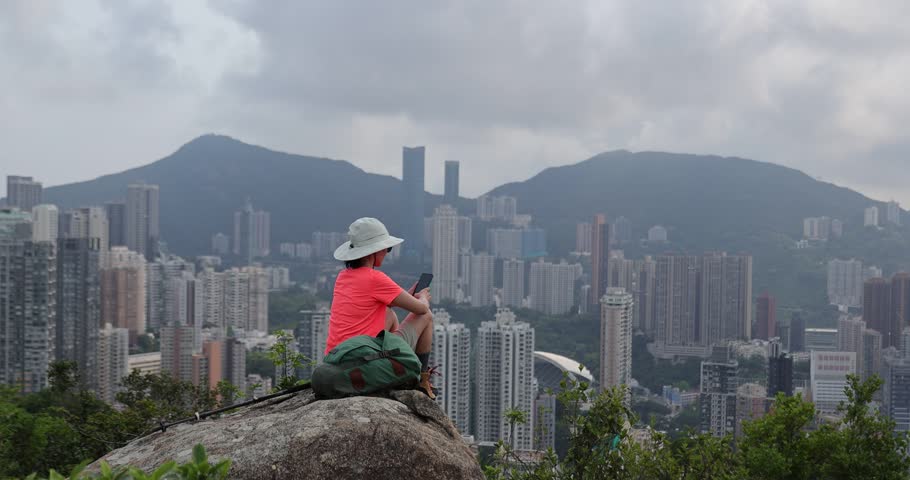 Woman hike using phone at the mountain top in Hong Kong	