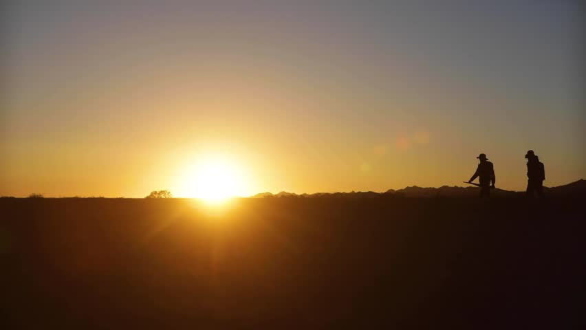 Silhouette of a group of hikers walking on a mountain ridge at sunset, cinematic backlighting.