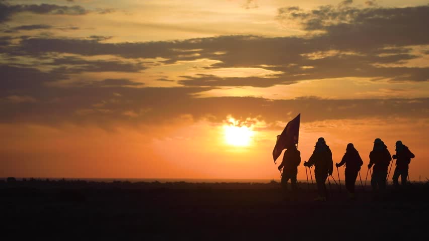 Silhouette of a group of hikers walking on a mountain ridge at sunset, cinematic backlighting.