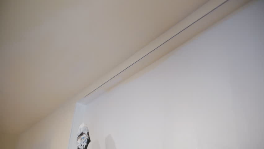 Person painting wall with brush near ceiling. Interior renovation and home improvement process