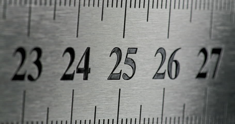 Slow Pan Over Metal Ruler. Smooth slow movement across extreme close-up of metallic ruler with black numbers and brushed surface.