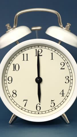 Classic white twin bell alarm clock ringing loudly at six o