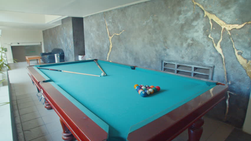 A modern billiard room interior featuring a professional pool table with blue felt, located within a luxury hotel lounge area for guest entertainment and relaxation.