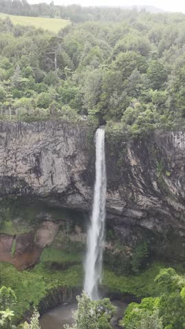 Vertical aerial view of Bridal Veil Falls Wairēinga waterfall flowing down cliff in Raglan New Zealand.