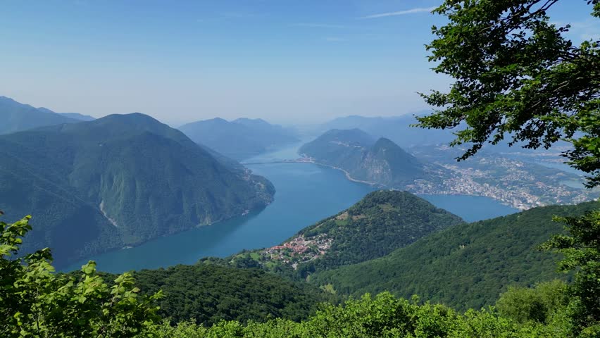 Wide scenic view of a lake and mountains in a lush green region.