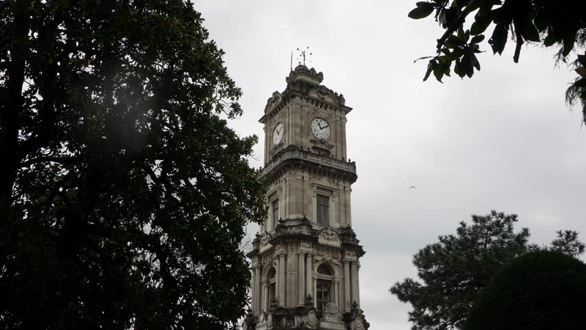Vertical shot of the historic Dolmabahce Clock Tower in Istanbul under a cloudy sky.