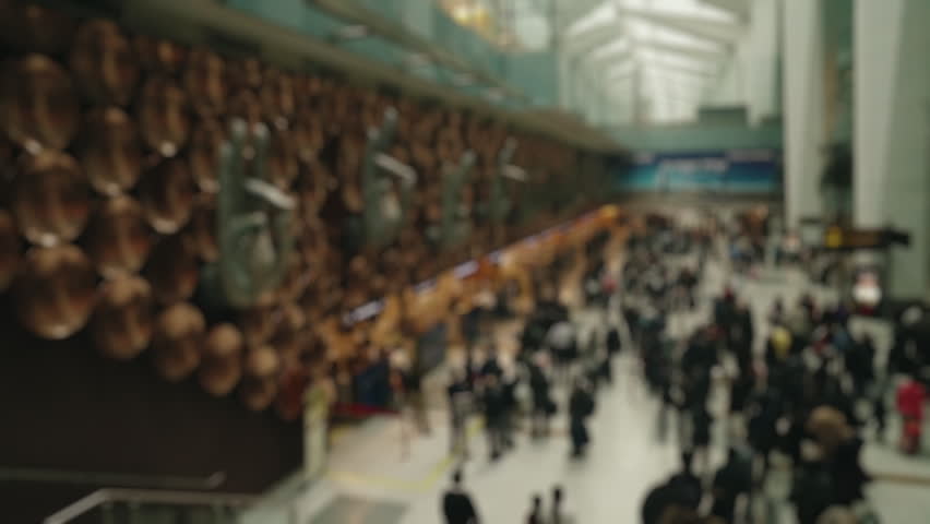 Out of focus high-angle view of a diverse crowd of anonymous people walking through the terminal of Indira Gandhi International Airport in New Delhi, featuring the distinctive mudra sculptures