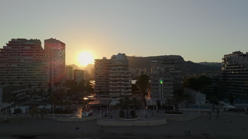 Calpe beachfront skyline at sunrise with modern apartment towers and golden morning light Spain.