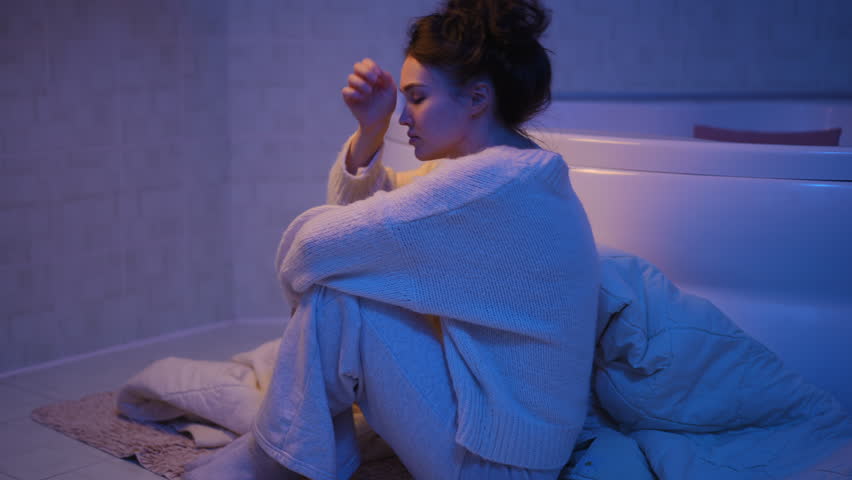 Young desolate woman feeling heartbroken and lonely. Worried and stressed female sitting on the bathroom floor suffers from depression