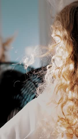 Hair fluttering in the wind. close-up, cute little girl is having fun.She stands in front of the fan, the air flows her curly hair, as if in the wind